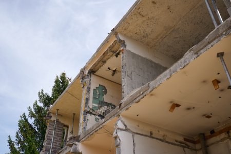 Przekrój budynku w stanie surowym z widocznymi stropami i podporami budowlanymi, ilustrujący nieprzewidziane wydatki i ukryte koszty budowy domu.