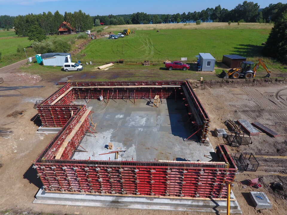Plac budowy New-House widziany z drona. Systemowe szalunki ścienne ustawione pod konstrukcję rezydencji, pokazujące profesjonalne zaplecze techniczne i organizację prac generalnego wykonawcy.