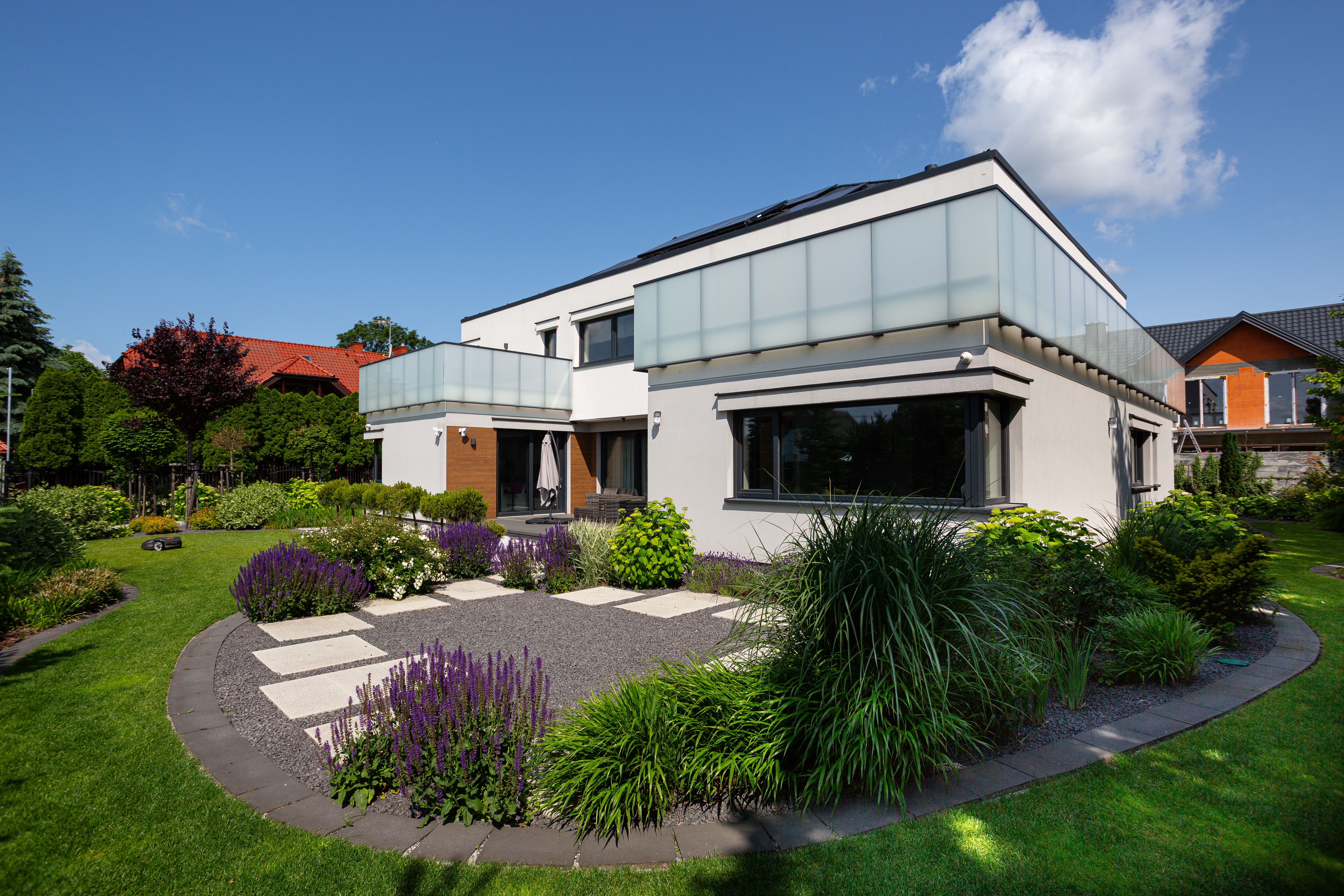 Nowoczesny dom jednorodzinny z ciemnym dachem wielospadowym i garażem, wybudowany kompleksowo przez firmę New-House. Widok z góry prezentuje gotową inwestycję zrealizowaną przed zmianami przepisów planistycznych w 2026 roku.