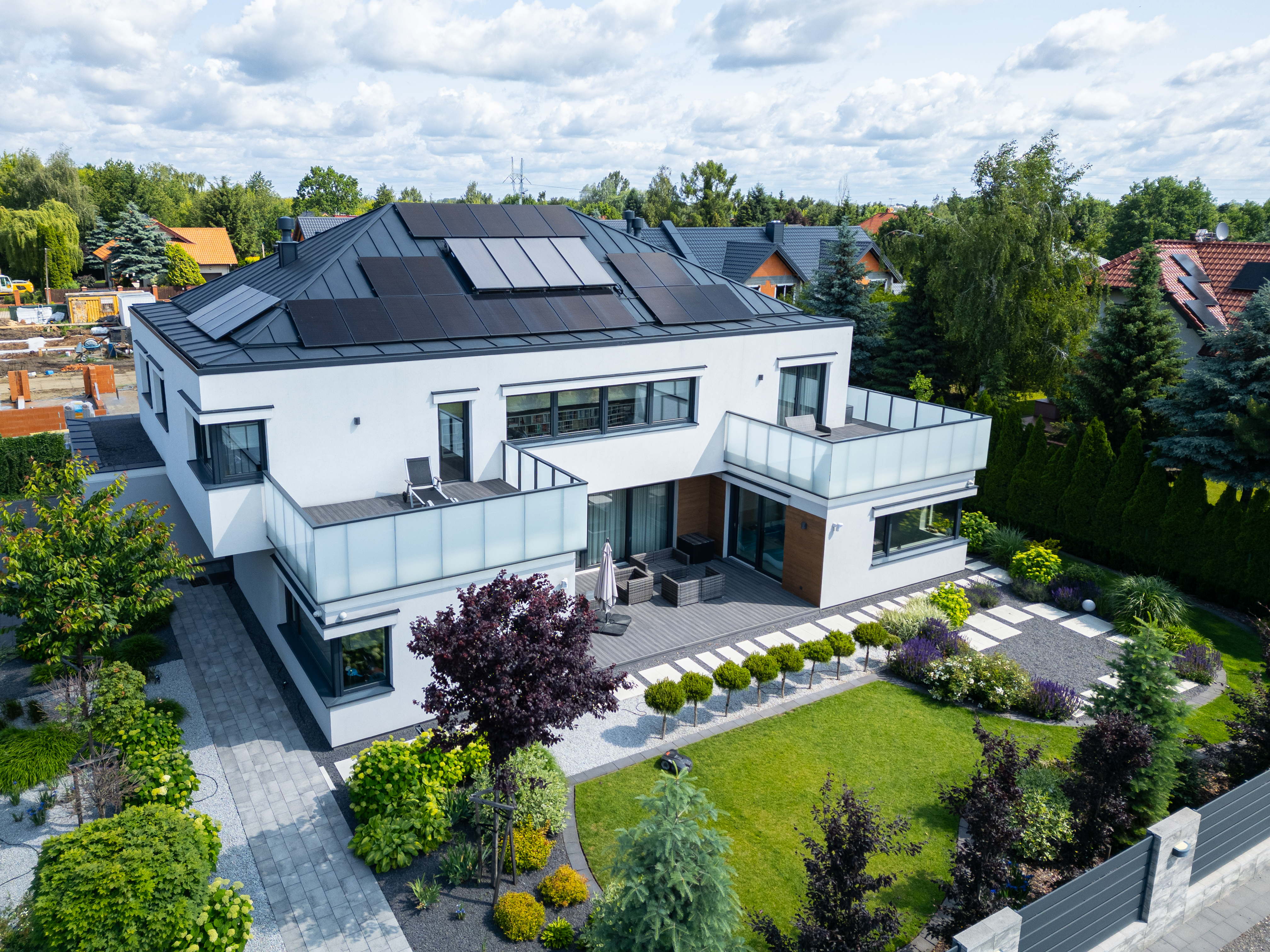 Gotowa realizacja New-House widoczna z drona; nowoczesny dom z panelami słonecznymi i ogrodem oddany w standardzie pod klucz.