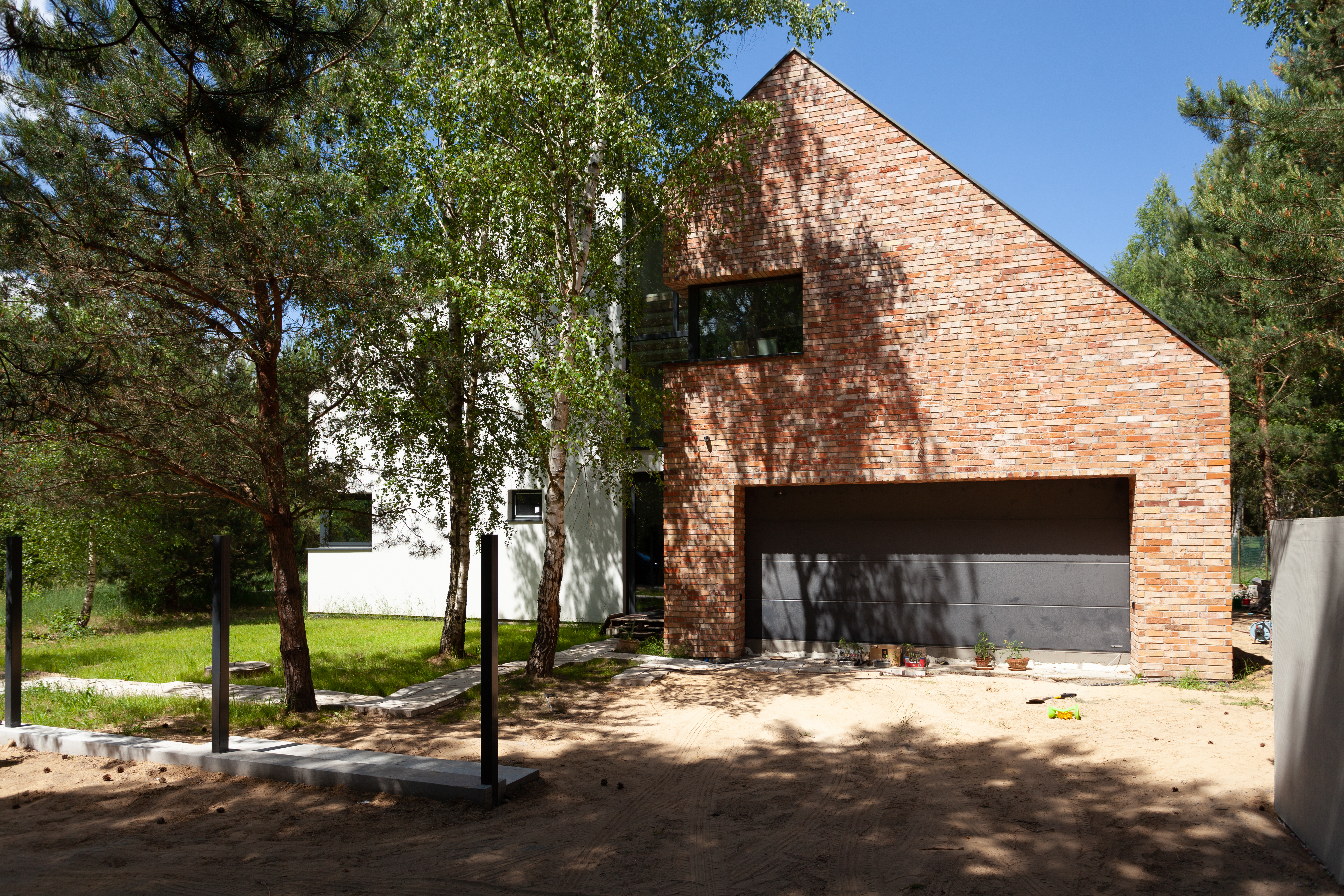 Nowoczesny dom z ceglaną elewacją w otoczeniu drzew - realizacja New-House