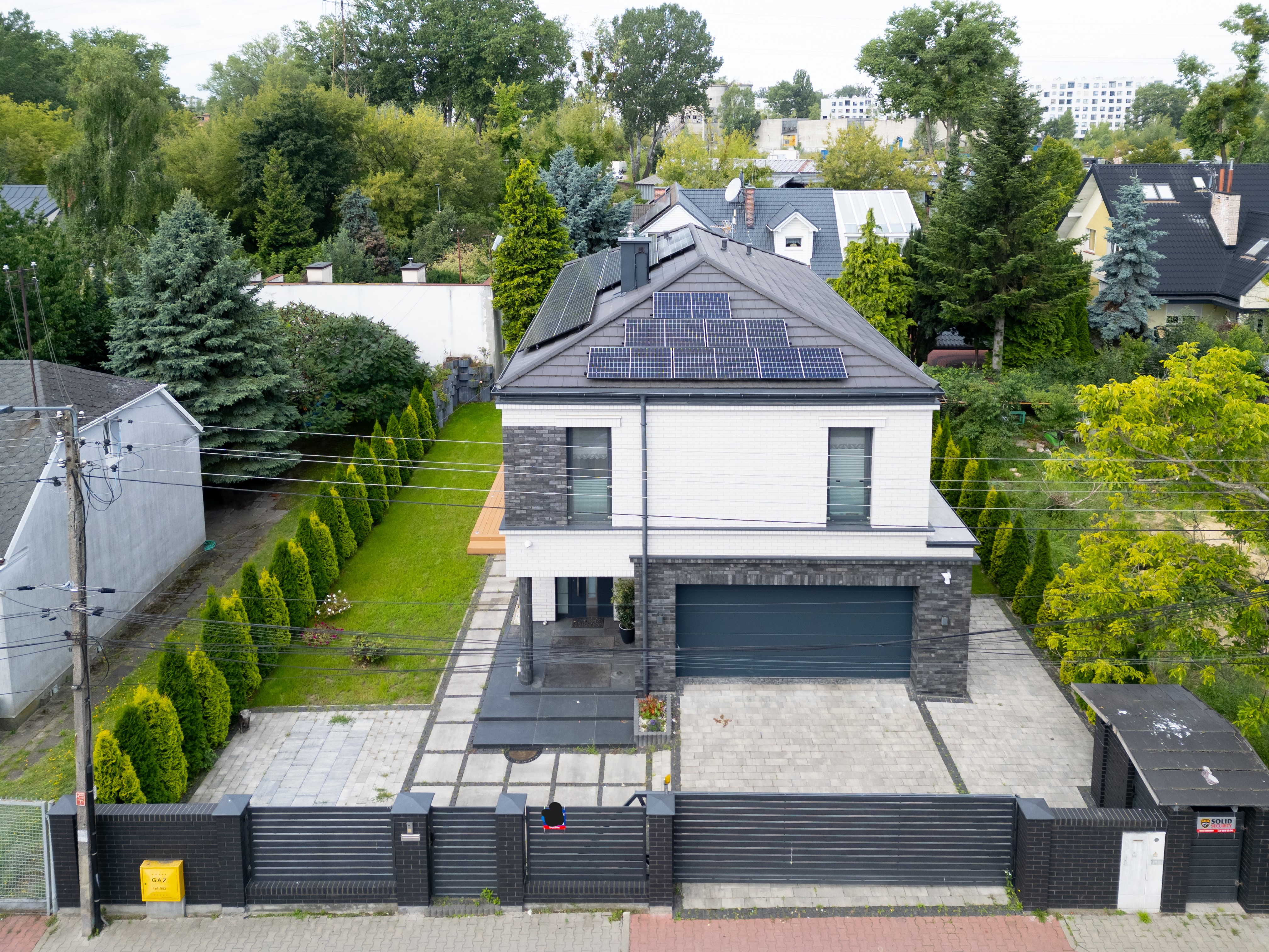 Widok z drona na dom jednorodzinny z instalacją fotowoltaiczną na dachu, wybudowany przez New-House w aglomeracji warszawskiej.