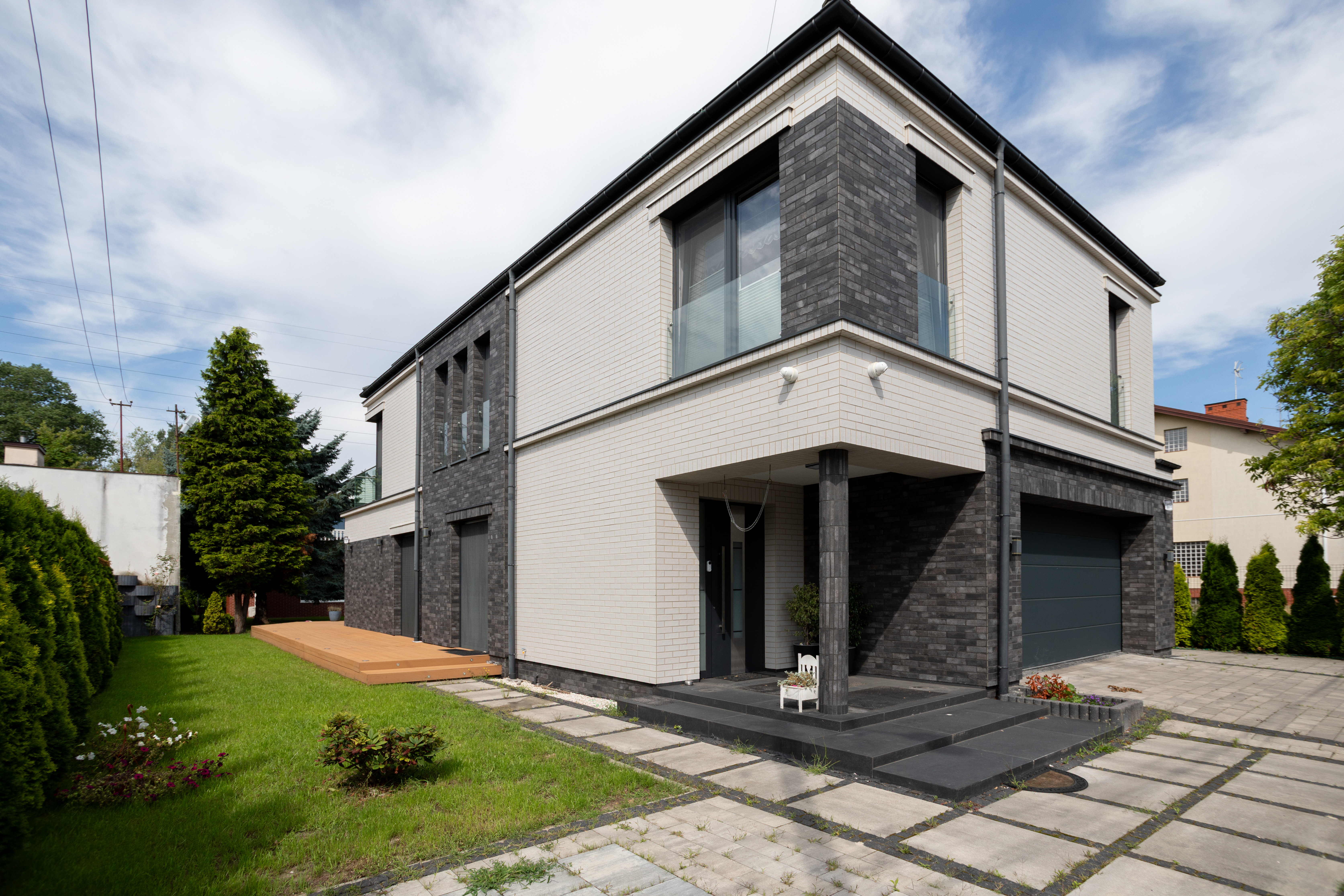 Piętrowy dom o nowoczesnej architekturze z jasną i ciemną elewacją - realizacja New-House